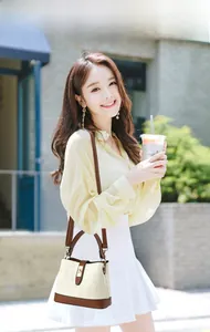 Close-up of cream plaid bucket bag with brown leather base and golden twist lock
