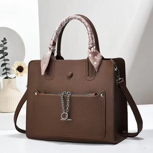Elegant brown pebbled leather handbag with silk scarf handle on a minimalist background
