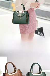 Detailed view of the swan metal buckle and gold ring handle on a vintage leather handbag