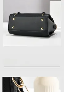 Close-up of black litchi pattern leather bag with gold protective feet and metal hardware