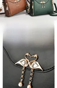 Detail of golden swan hardware with tassel on a retro faux leather tote handbag