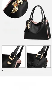 Detail of black pebbled leather tote featuring cat charm and pink edge painting