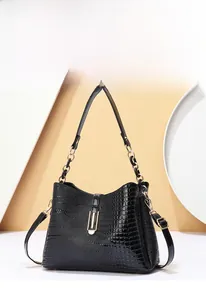 Detail der glänzend schwarzen Kroko-Lederhandtasche mit elegantem goldenem Kettengriff