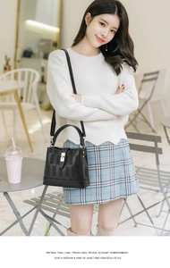 Detail of black pebbled leather bucket bag with checkered texture and gold buckle