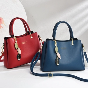 Red and blue textured leather handbags with adjustable straps and leaf charm