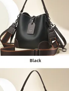 Detail of black bucket bag with lychee texture, brown leather trim and two shoulder straps