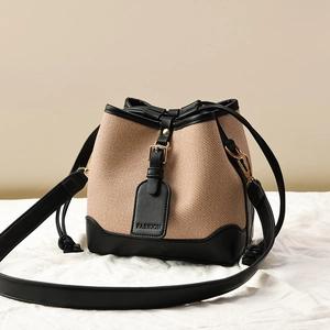 Sac seau tissé avec garniture en cuir noir et bandoulière sur un fond de couleur neutre