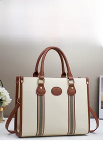 Detail of cream pebbled leather tote bag with brown straps and golden metal clips