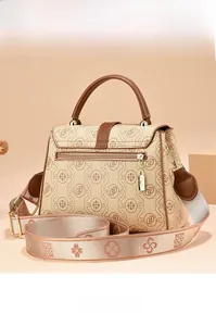 Detail view of the back zipper pocket on a beige monogram crossbody bag with wide strap