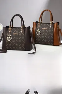 Détail d'un sac cabas en cuir texturé avec imprimés logo et pendentif cœur doré