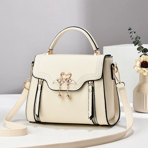 Elegant off-white crossbody bag with swan buckle and pearl detail on display