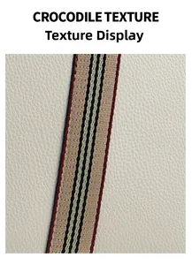 Detail showing cream-white crocodile textured leather with striped woven shoulder strap