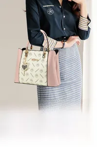 Détail du sac cabas rose et crème avec imprimé monogramme et breloque en cœur