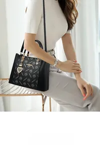 Détail du sac à main monogramme noir avec breloque cœur en métal et décoration de perles