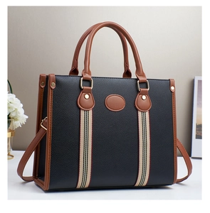 Detail of black pebbled leather tote bag with striped webbing and brown leather trim