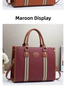 Detail of burgundy tote bag with litchi texture and striped strap on a minimalist stand