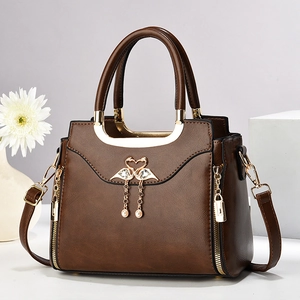 Vintage brown trapezoid handbag with swan metal ornament and tassel on white pedestal