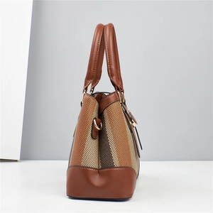 Detailed side view of the woven tote bag showing brown leather handles and gold hardware