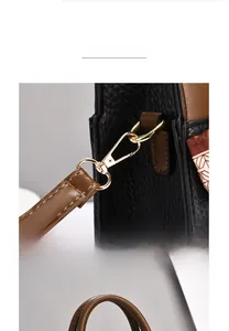 Close-up of polished gold-plated metal clasp on black and brown lychee leather bag
