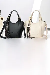 Détail de sacs cabas en cuir grainé noir et beige avec breloques à pompons