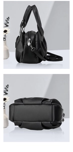 Vue détaillée du sac en cuir noir montrant les plis latéraux et les ferrures argentées