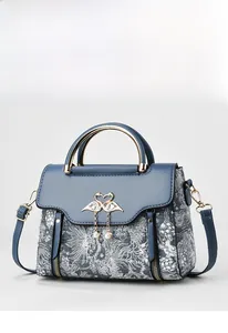 Detail of elegant handbag with navy leather, floral fabric and golden swan clasp