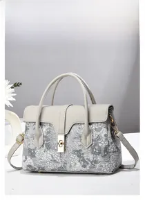 Macro detail of landscape jacquard fabric and golden twist lock on grey bucket handbag