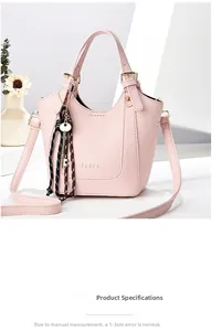 Vue détaillée du cuir rose grainé litchi et du pendentif clé en métal sur le sac