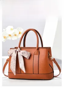 Détail du sac seau caramel en cuir grainé avec un élégant foulard noué à la poignée