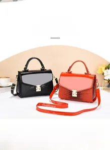 Close-up of glossy crocodile embossed leather handbag with gold lock and metal strap