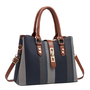 Three-quarter view of a navy and white striped tote bag with brown leather handles
