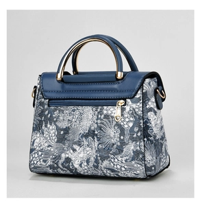 Detail of floral jacquard handbag featuring semi-circular gold metal handles and zip pocket