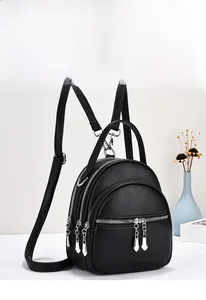 Detailed view of black litchi grain leather backpack with multiple silver zippers