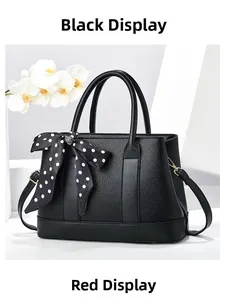 Détail du sac seau en cuir grainé noir avec foulard à pois et finitions métalliques dorées