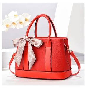 Détail du sac seau rouge en cuir grainé avec foulard à pois et finitions dorées chic