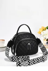 Detail of black quilted round crossbody bag with a patterned wide shoulder strap