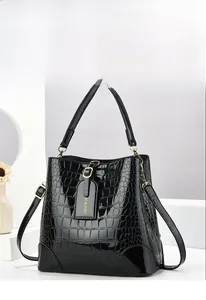 Macro shot of black crocodile embossed bucket bag with polished gold hardware and logo tag