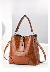 Detail of brown crocodile pattern bucket bag featuring gold hardware and logo tag