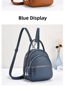 Detailed view of mini blue faux leather backpack with multiple zip pockets and silver hardware