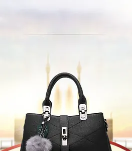 Detail of black lychee grain leather handbag with silver buckle and plush pompom charm