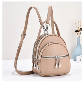 Macro detail of beige pebble leather mini backpack showing triple zipper compartments