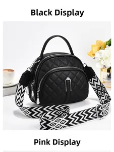 Close-up of black quilted crossbody bag with geometric wide strap and zipper detail