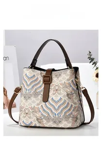 Dettaglio della borsa a secchiello beige con ricamo a nuvole e manico in pelle marrone