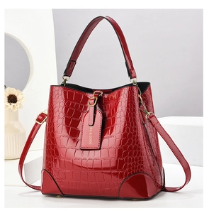 Close-up of red crocodile-pattern bucket bag with gold hardware and logo tag detail