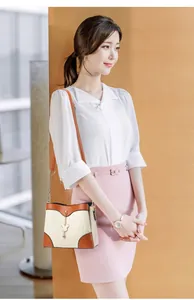 Detail of cream woven handbag with brown leather trim and gold chain strap worn by model