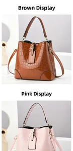 Detail view of yellow and pink crocodile texture bucket bags with metal charms and straps