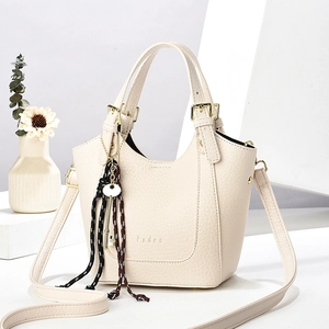 Sac seau blanc crème avec texture litchi, deux poignées et pendentif tressé