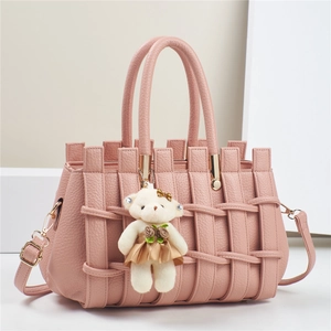 Pink woven leather tote bag with gold hardware and a cute bear charm on a white stand