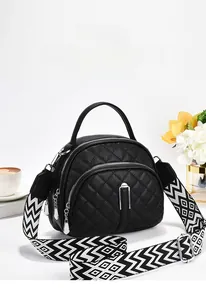 Détail du sac matelassé noir avec trois zips argentés et large bandoulière à motifs