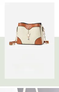 Detail of crossbody bag featuring cream woven texture, brown trim and rabbit charm